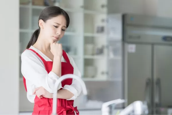 キッチンに立って悩む女性